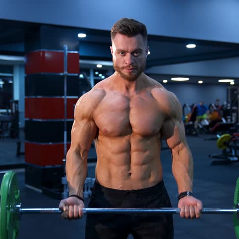 male athlete with strong body and naked torso lifts barbell in modern gym. slow motion