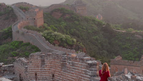 a woman in red watches over a wall lining the hills