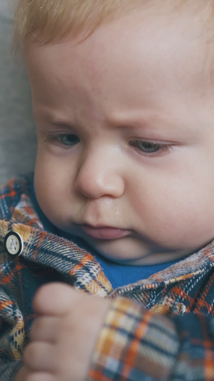 happy small baby plays with glass dropper sitting on mother knees in light room extreme close view