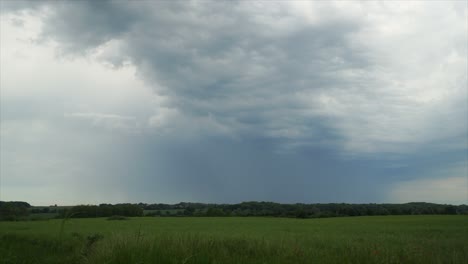 Nubes-Tormentosas-Oscuras-Pasan-La-Cámara-En-Movimiento-Rápido-A-Través-De-Campos-Verdes