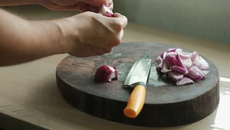man slicing red onion on wooden chopping board. - closeup shot