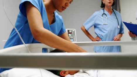 nurse placing an oxygen mask and adjusting iv drip to patient in emergency room