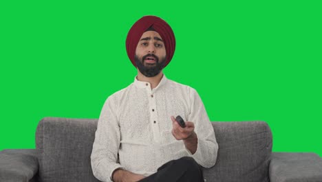 hombre indio sikh cansado y somnoliento viendo la pantalla verde de la televisión