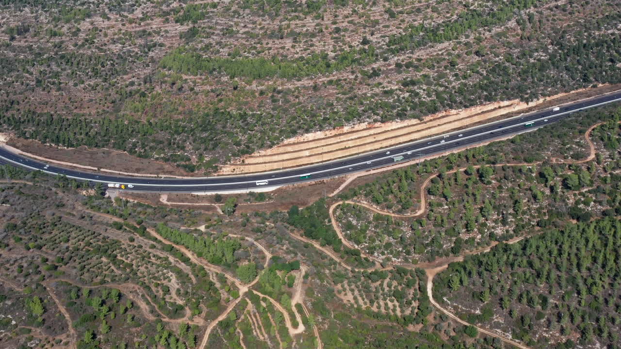 Aerial footage over large Highway between the mountains and pine forest