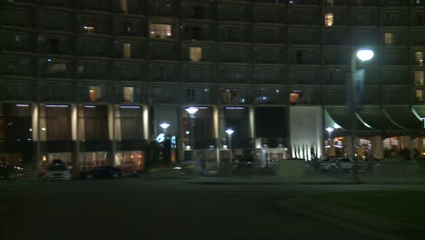 a car travels along a street passing the century plaza at night in century city los angeles as seen through the side window