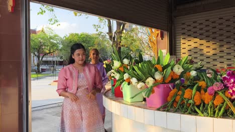 thai women preparing floral offerings at a temple