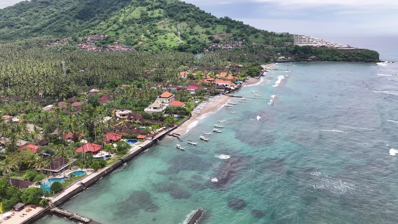 Drone flying to hotel building on Balinese Coast, Candidasa Beach. Peaceful holiday, Indonesia.