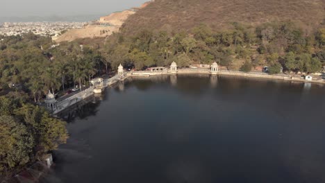 Udaipur-lake-Pichola-bank-surrounded-by-stone-dam-in-Rajasthan,-India---Aerial-Panoramic-shot