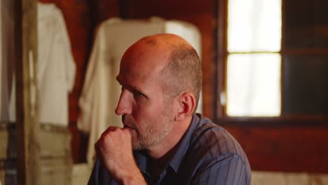 thoughtful bald man smoking a cigarette in a rustic cabin