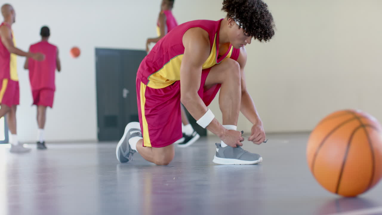 Jovem afro-americano amarra o cadarço do tênis na quadra de basquete