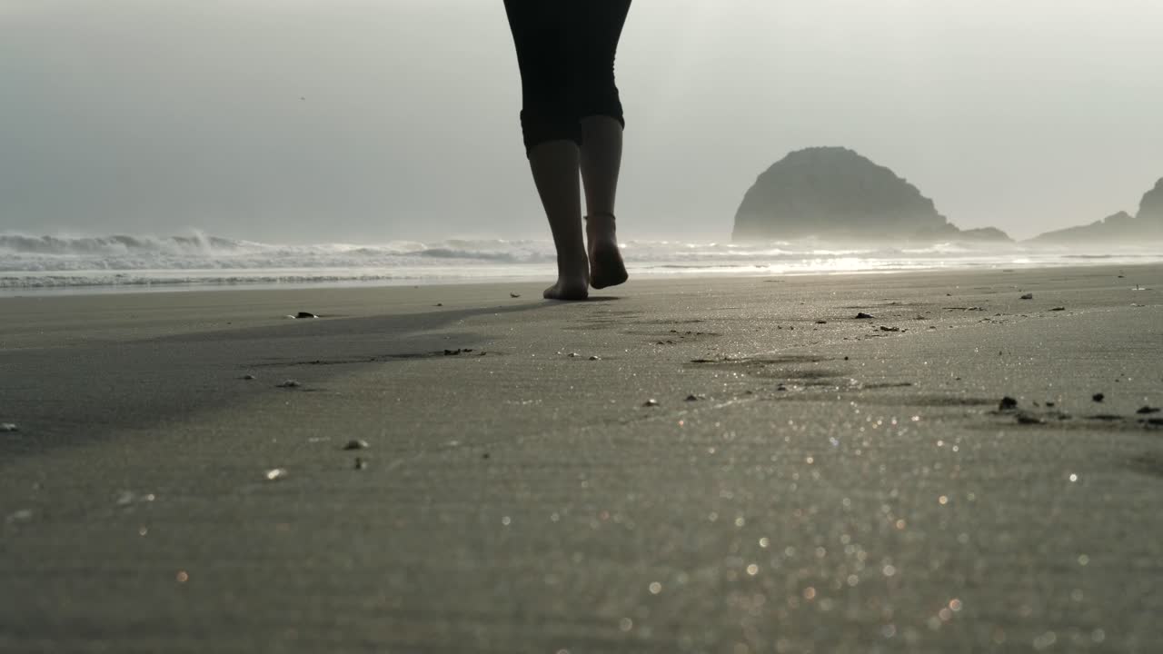 석양에 맨발로 모래 위를 걷는 여자