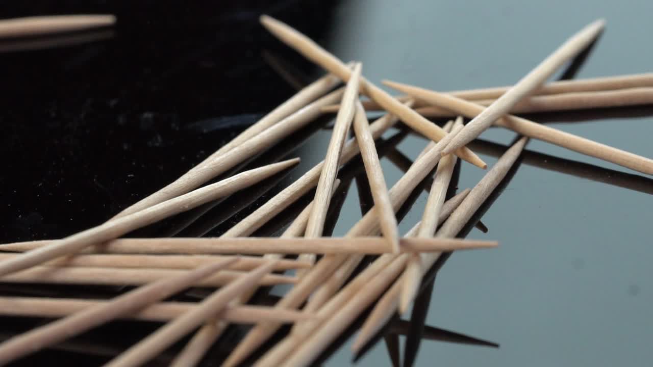 Macro shot of wooden toothpicks scattered on a reflective surface