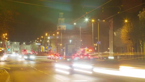 Timelapse-of-city-rush-hour-traffic-over-the-Liepaja-tram-bridge,-city-landscape-at-night,-traffic-light-streaks,-fast-moving-trams,-distant-wide-shot