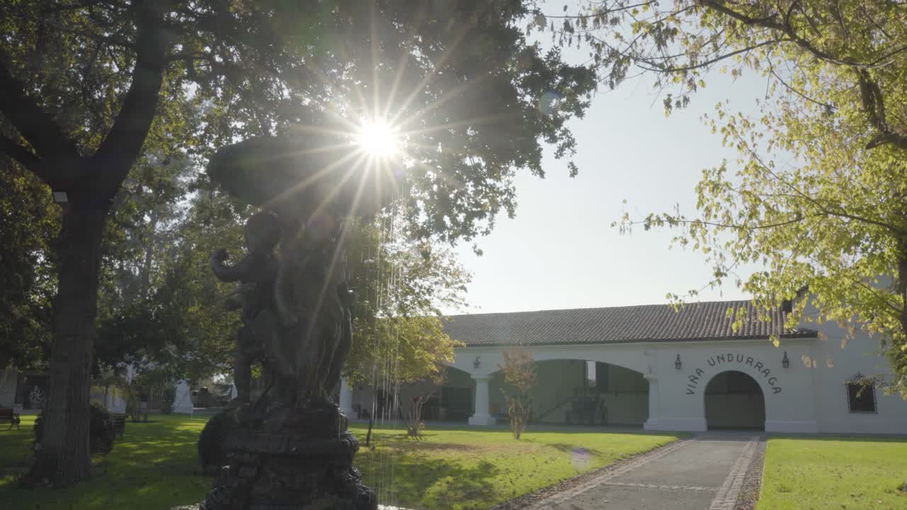 с рук в центральном фонтане виноградника ундуррага с солнцем на заднем плане, талаганте, чили