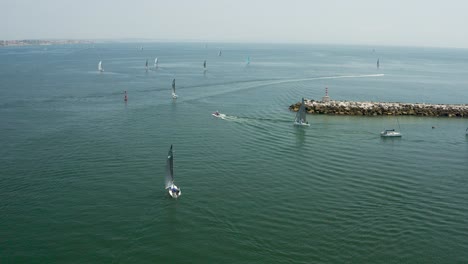 Sb20-sailboats-leaving-Cascais-marina,-fleet-of-Yachts-navigating-on-sea