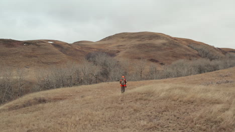 A-Adult-Male-Hunter-walking-towards-the-thick-brush-at-the-foot-of-a-small-hill-close-to-Swift-Current,-Saskatchewan,-Canada