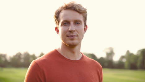 portrait of a man smiling and looking at camera in the park