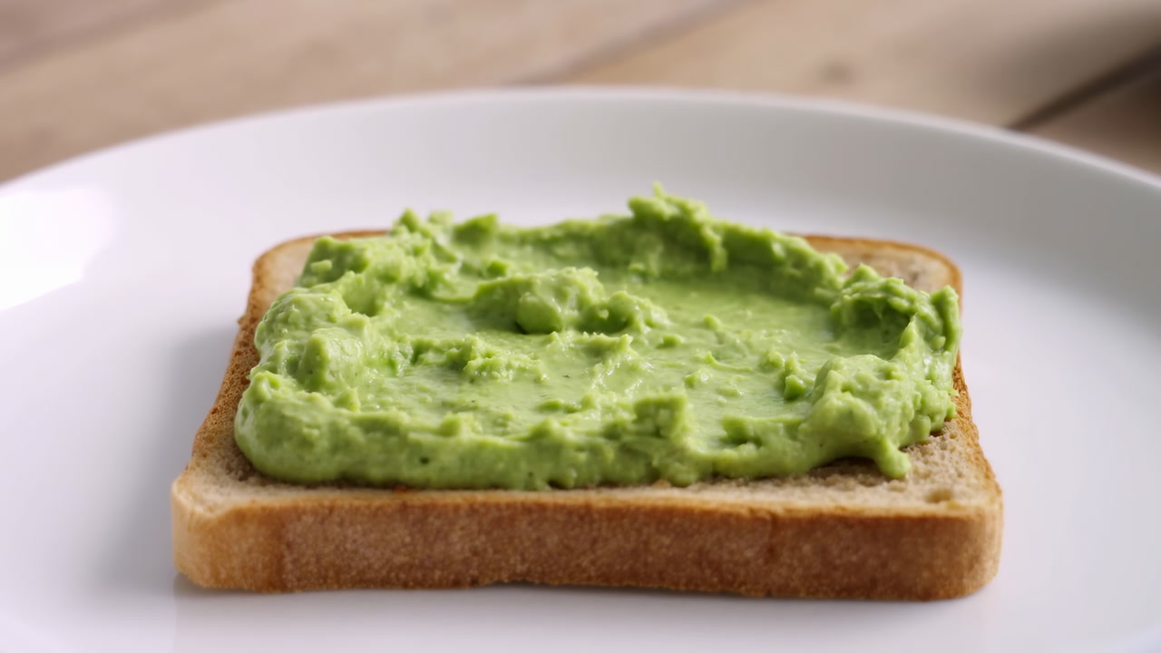 Green Avocado Spread On Toasted Bread, White Ceramic Plate On Wooden Tabletop, Creamy Mashed Texture