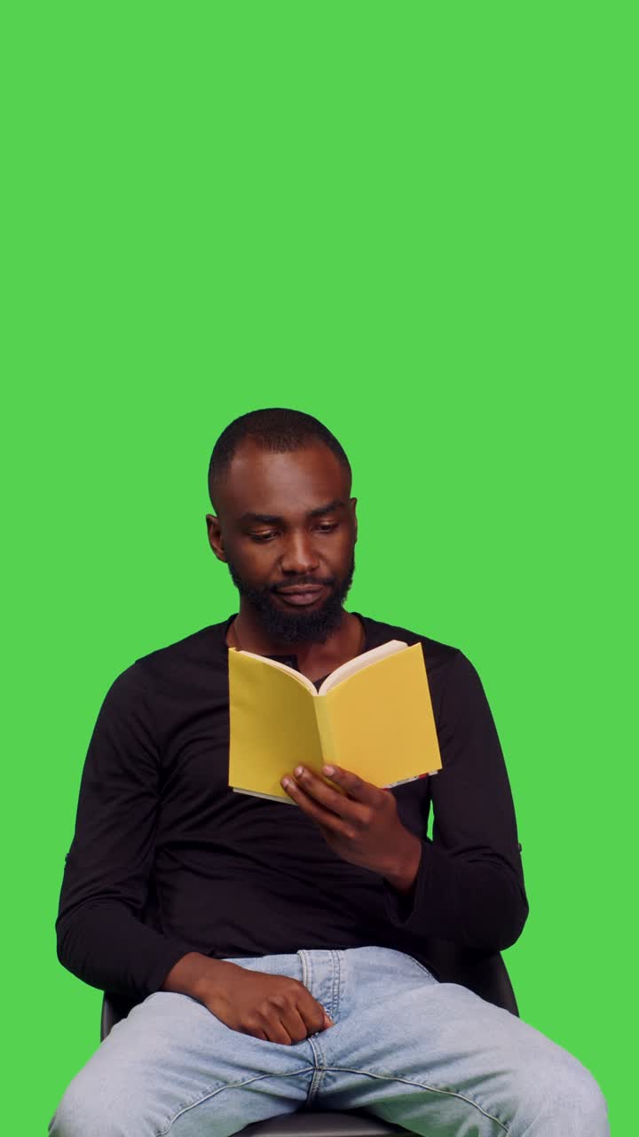 Vertical video: Front view of african american man being captivated by novel