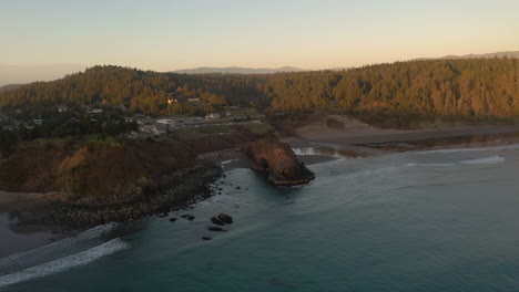 scenic view of battle rock wayside park in port orford, oregon with dense mountainous landscape in background on a dramatic sunset