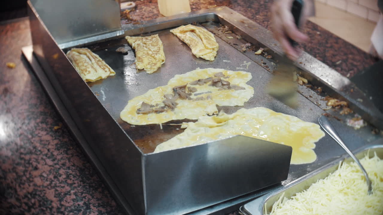 el chef voltea tortillas de champiñones y queso en una parrilla caliente en un restaurante