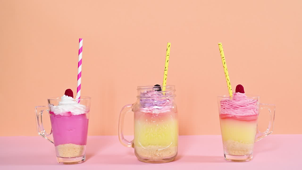 오렌지 분홍색 파스텔 테마에 회전하는 크림과 으로 푸딩의 세 컵. 움직임을 멈추십시오