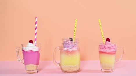 tres tazas de pudines con crema y paja girando en el tema pastel rosa naranja. detenga el movimiento