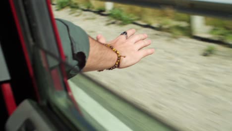 Male-Hand-Through-Open-Window-in-Airflow-of-Driving-Car,-Close-Up