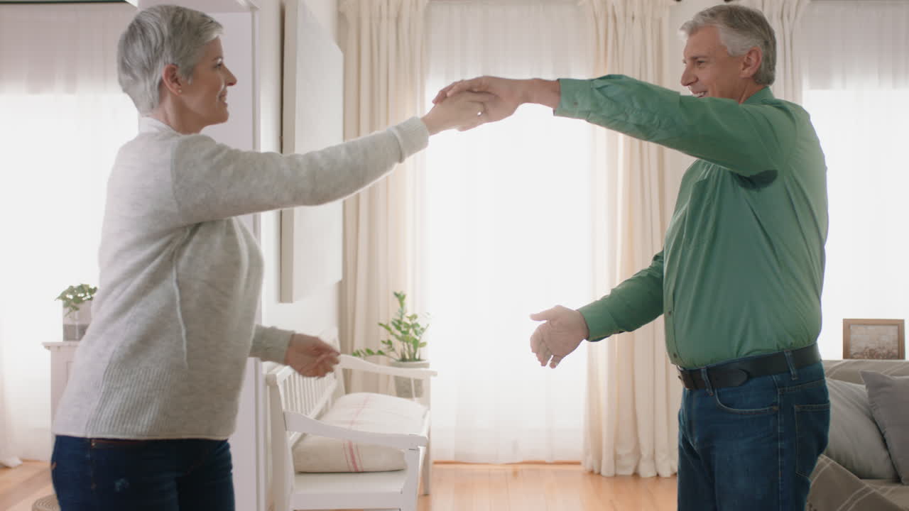 feliz pareja madura bailando en casa disfrutando de un baile romántico juntos celebrando el hito de la relación teniendo una jubilación pacífica 4k