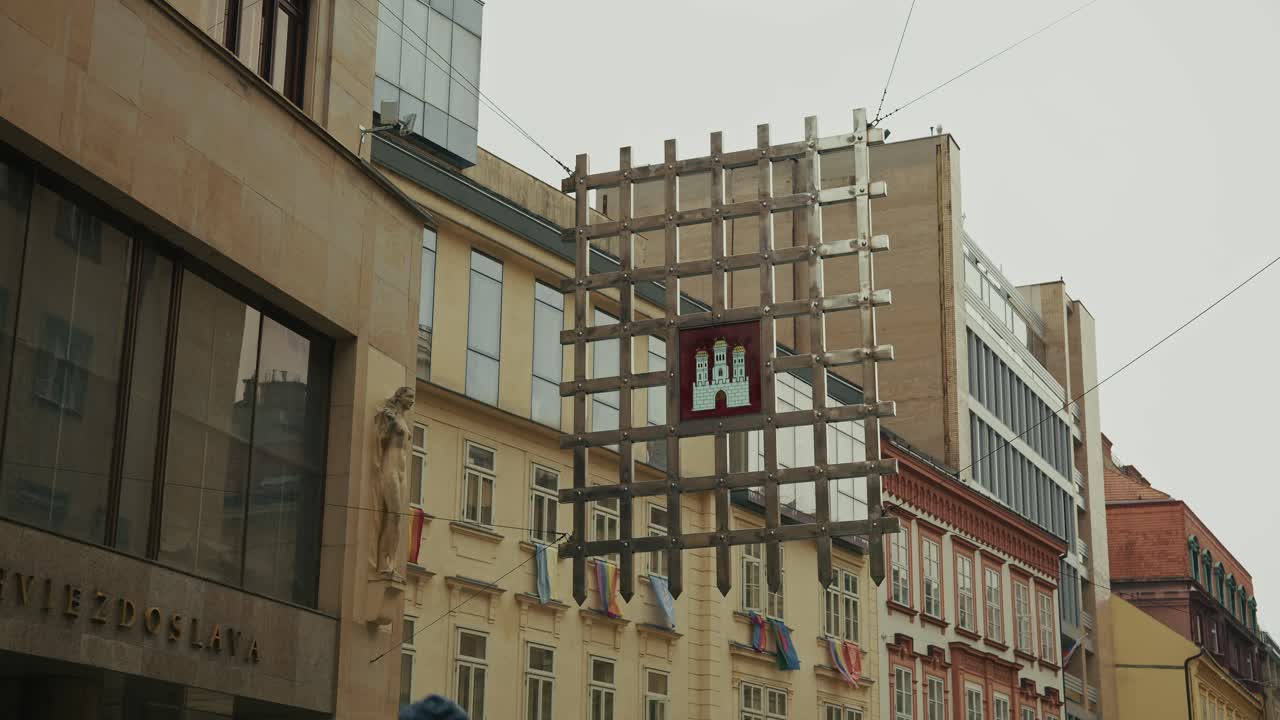 Bratislava city emblem displayed on a suspended metal grid in an urban setting