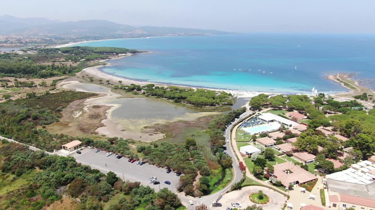 This is a forward motion video of a city that sits alongside a coastline with crystal clear water. The city has various sport activities of tennis courts and soccer fields