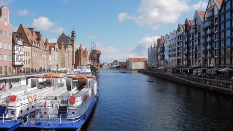 ferry boat dock at motlawa river with typical buildings in gdansk old town at daytime in poland. - wide static