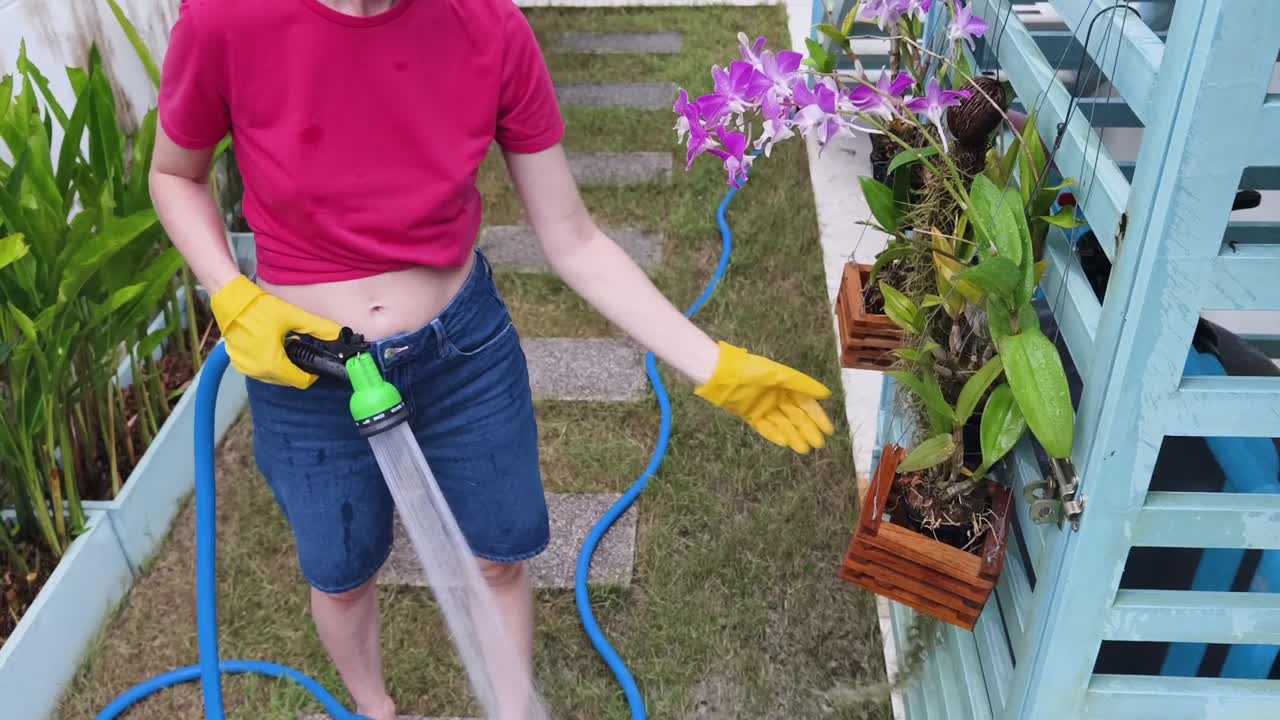 Woman Watering Orchids in Garden