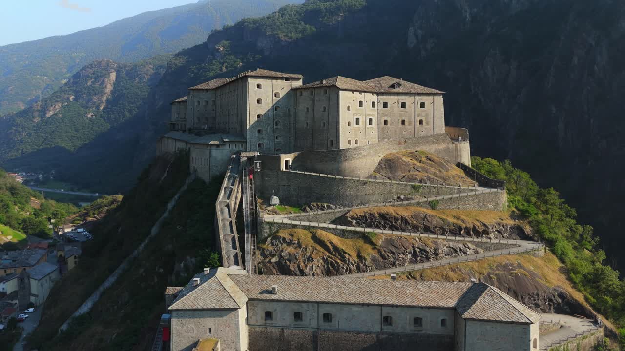Forte di Bard in Valle d'Aosta, Italia, circondato da montagne e vegetazione lussureggiante, vista aerea.