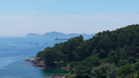 Forested-Mountain-Revealed-Industrial-Vessel-Sailing-On-Tropical-Seascape