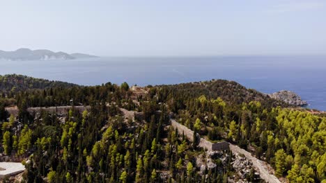 Camino-De-Montaña-Hacia-El-Castillo-De-Assos-En-Asos,-Kefalonia-Grecia-En-Una-Tarde-Nublada-Por-El-Murciélago-Agia-Kyriaki---Toma-Aérea