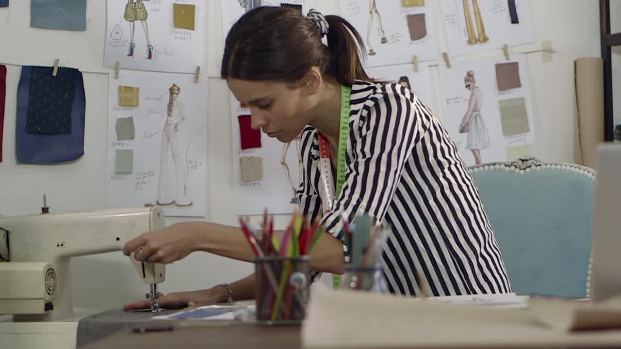 Mujer concentrada cosiendo tela en una máquina en un estudio de moda