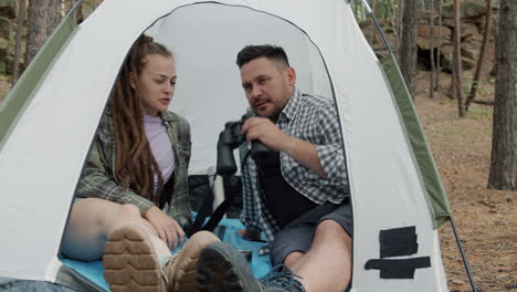 couple camping in the forest with binoculars