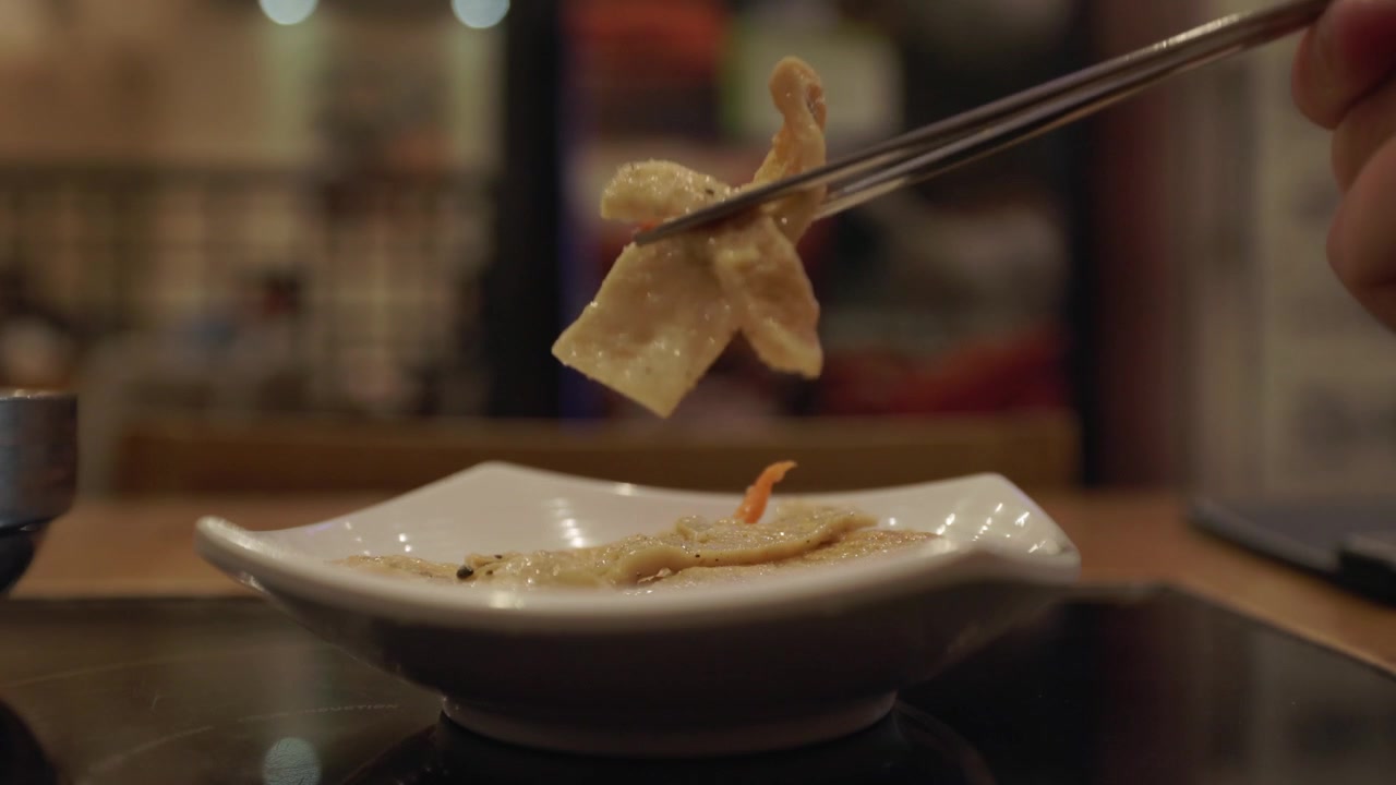 Dumpling Held With Chopsticks Above A White Plate, Prepared Food And Serving Presentation. Close-up Shot