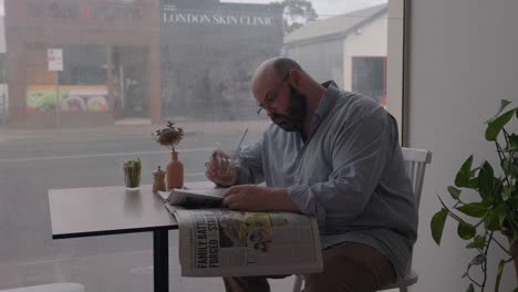 man sitting in coffee restaurant shop reading news paper close up