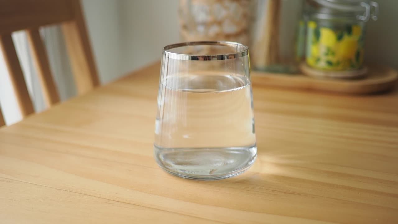 Bicchiere trasparente di acqua fresca su un tavolo di legno.