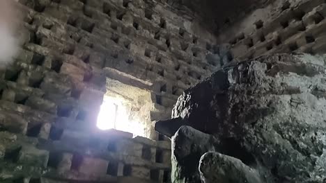 inside old penmon priory dovecot with stone wall nesting box looking up at window light