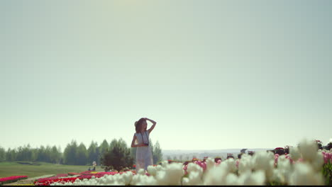 Young-lady-taking-off-sunhat-in-flower-field.-Girl-taking-photo-in-flower-field.