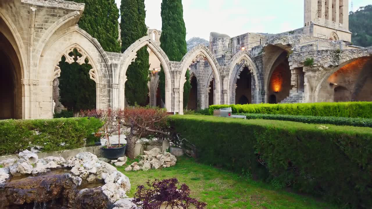Kybele Abbey with green firs, ornamental bushes an stone fountain. Panoramic shot. Slow motion. Kyrenia, Cyprus