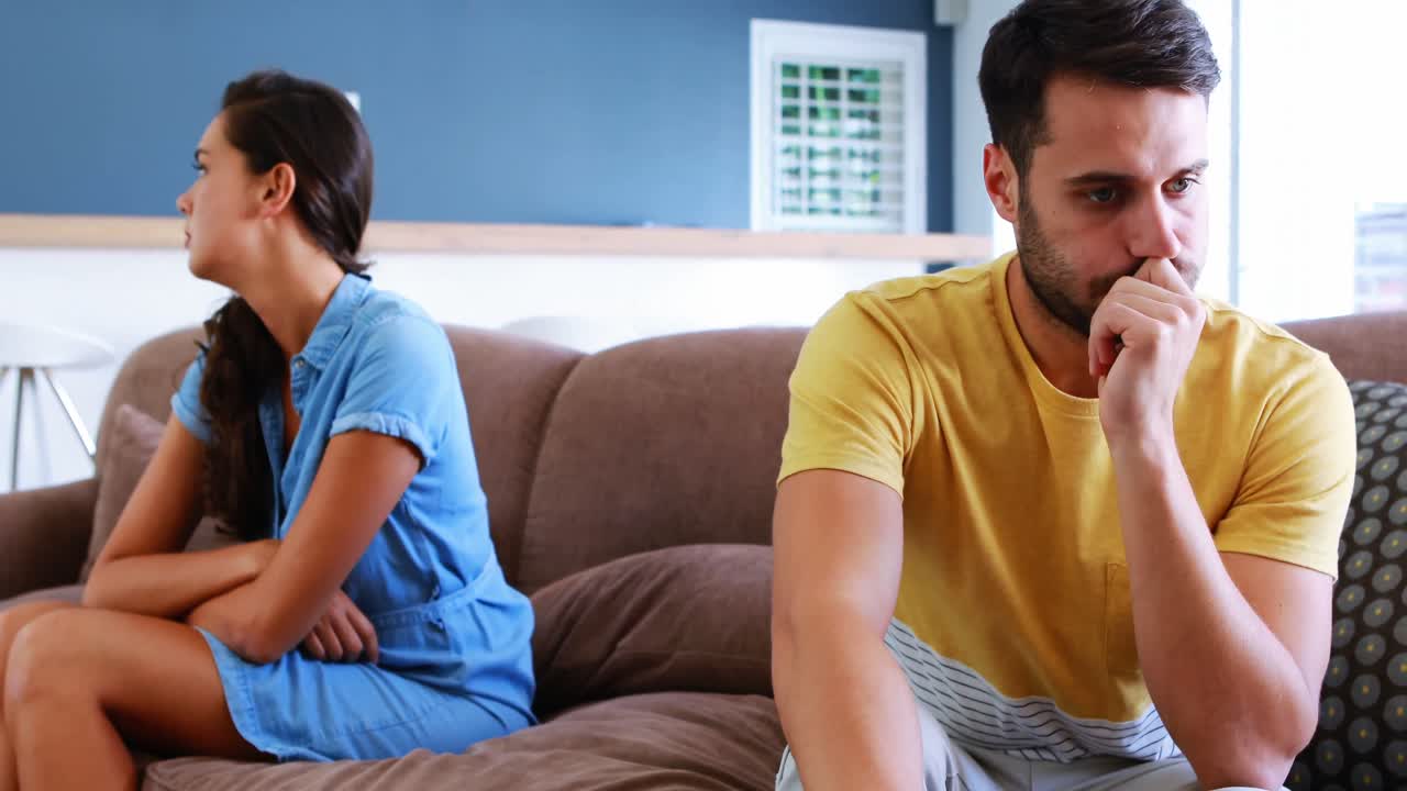 Couple ignoring each other in living room