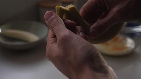 cámara lenta de una persona pelando plátano fresco sobre un banco de cocina con tazones de cocina en el fondo