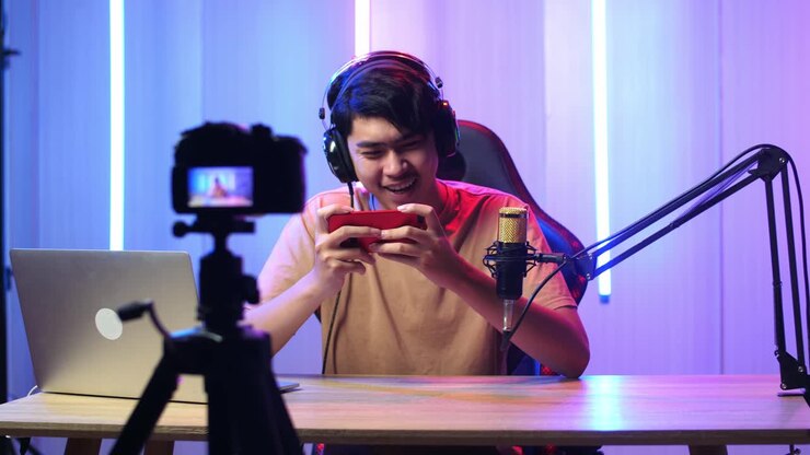 Uomo asiatico entusiasta che gioca a un videogioco con il telefono cellulare mentre trasmette in diretta con la telecamera.