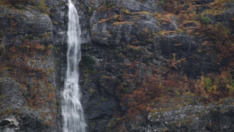 Cerrar-La-Sartén-Sobre-Una-Enorme-Cascada-Sobre-Un-Acantilado-Rocoso-Con-árboles-De-Colores-Otoñales