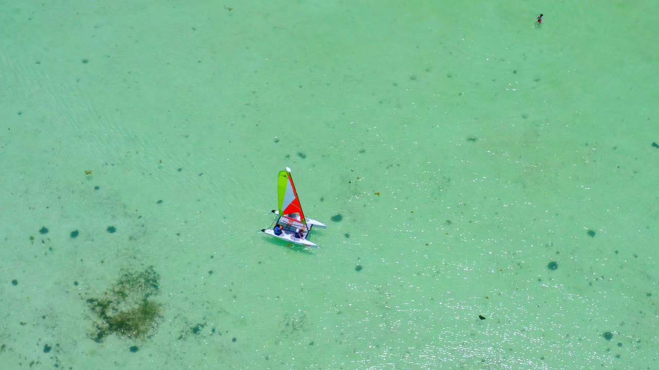 Aerial view around a small catamaran in shallow, turquoise sea, in Dominican republic - circling, drone shot