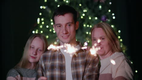 A-happy-family-celebrates-the-new-year-at-the-Christmas-tree,-holding-burning-sparklers